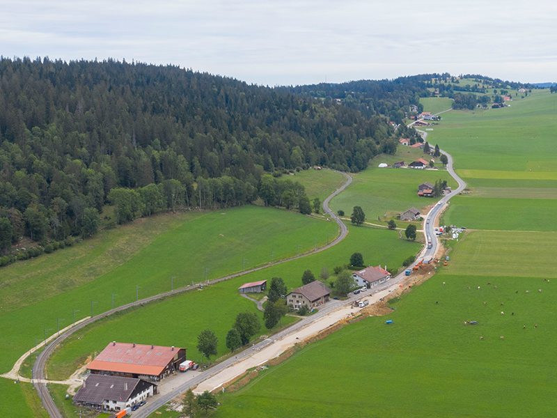 Aerial view of road construction works cutting through green countryside