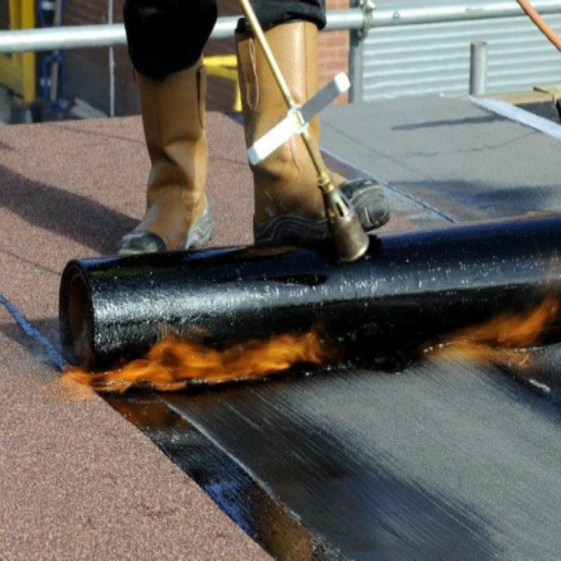 Torch-applied waterproofing membrane being laid on a roof